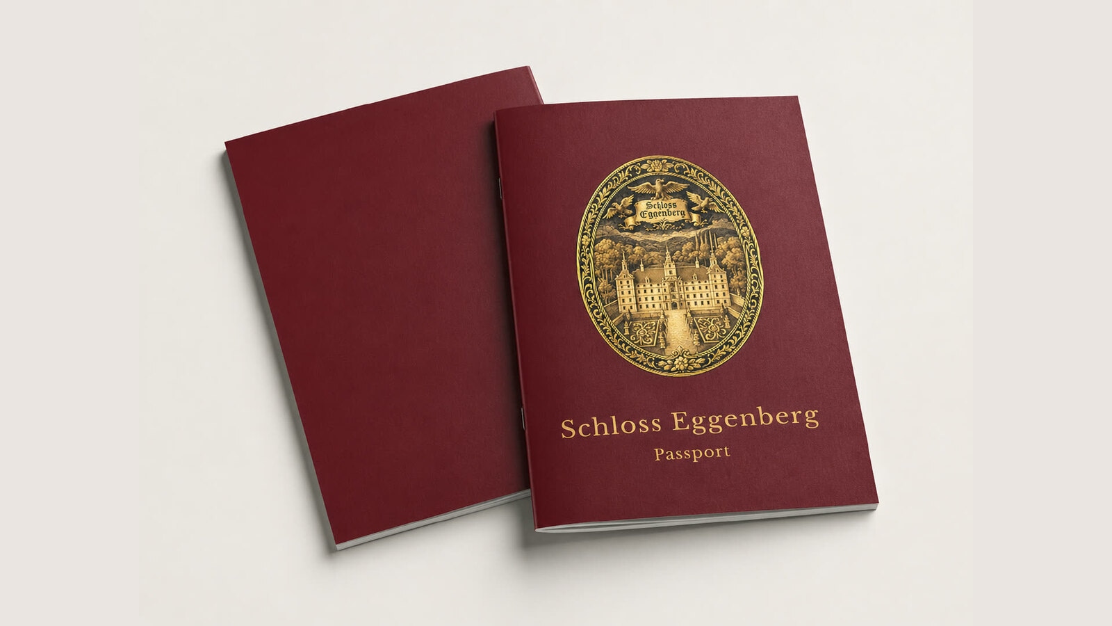 Mockup of a burgundy Schloss Eggenberg passport booklet with a gold oval palace emblem on the cover.